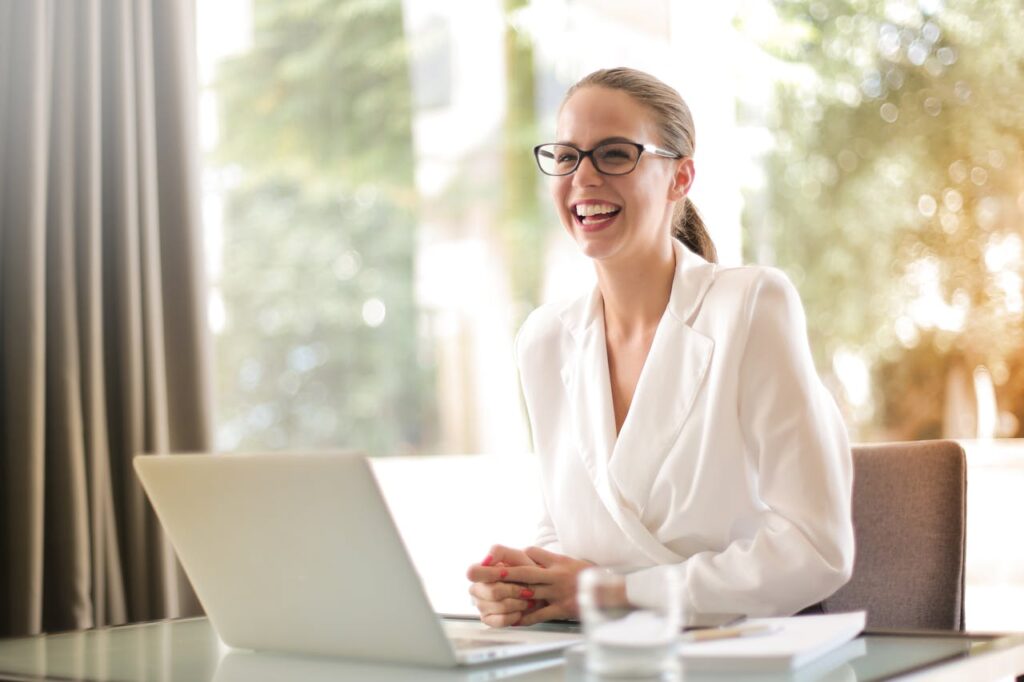 Photo RA DGF Cheerful businesswoman in glasses working on a laptop, in a bright and modern office setting.